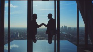 Two gentlemen shaking hands before a window overlooking large city