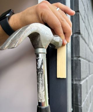 A person wearing black smartwatch using a screwdriver to install a sliding door