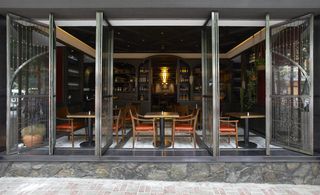 Catalunya, Hong Kong, China. A restaurant with tables and chairs, wooden wall shelves and large sliding doors.