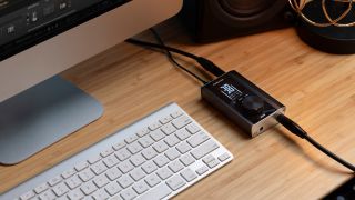 A Positive Grid Riff audio interface on a desk next to an iMac keyboard