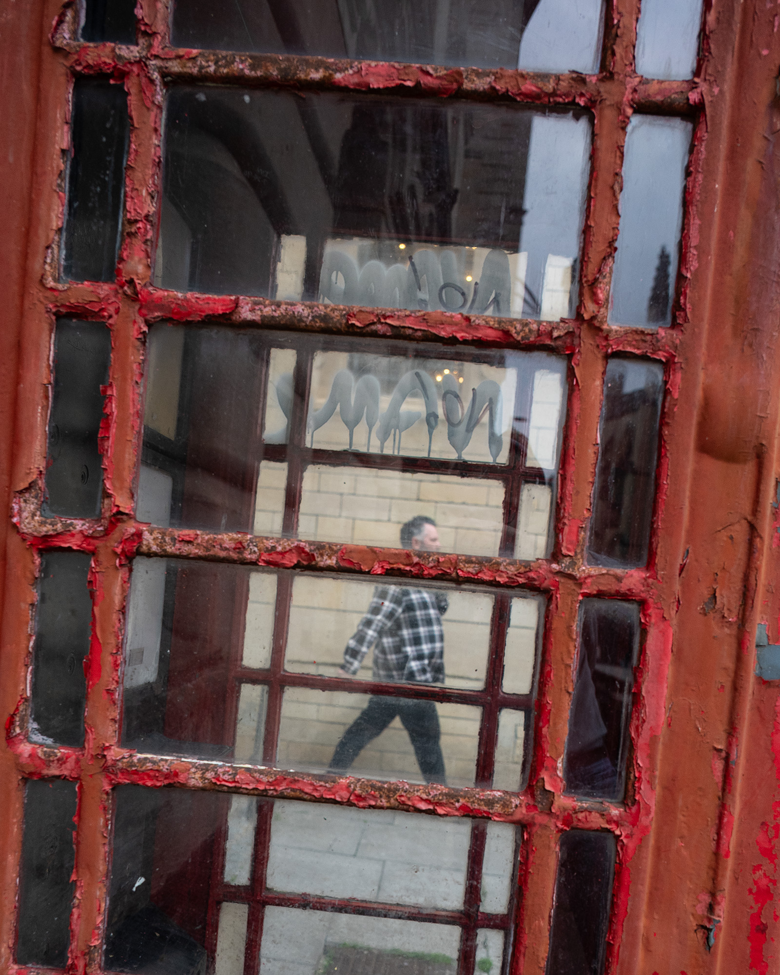 Street photograph of red telephone box with man walking by