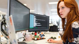 Woman using the best web design software on two desktop monitors