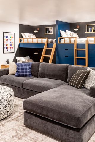 A bunk room with bunk beds and a grey sofa