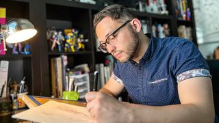 Artist in residence; Joe Quinones sits at a desk drawing