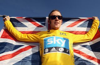 Bradley Wiggins in the Tour de France yellow jersey holding a British flag behind his back