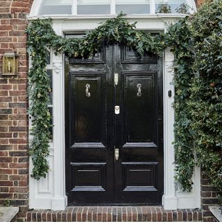 black front double doors to property with Christmas garlands draped around