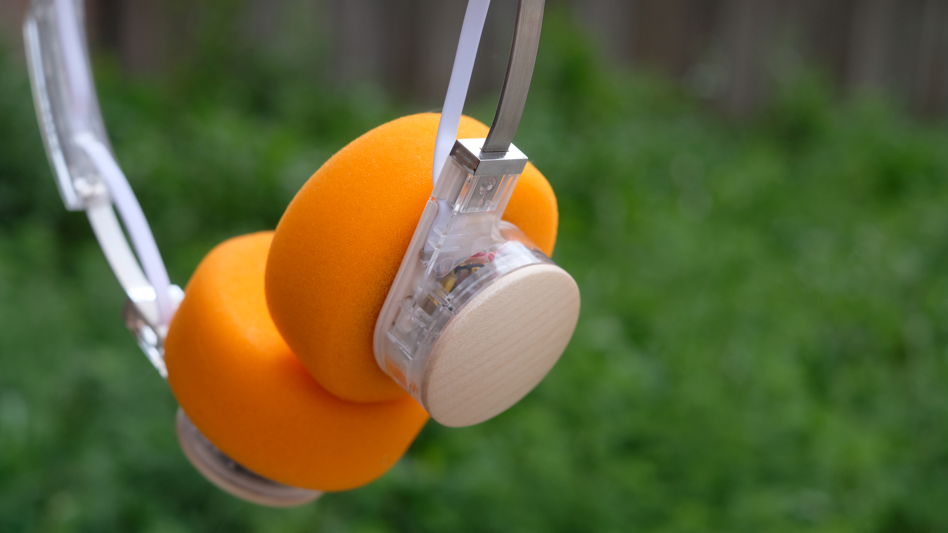 A photograph of the FiiO EH11 over-ear headphones with a transparent frame and orange foam earpads.