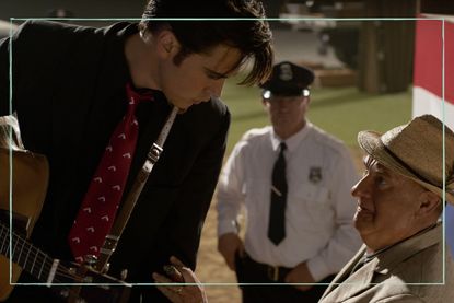 a still of the Elvis movie showing Austin Butler with a guitar looking down on Tom Hanks as Colonel Tom Parker