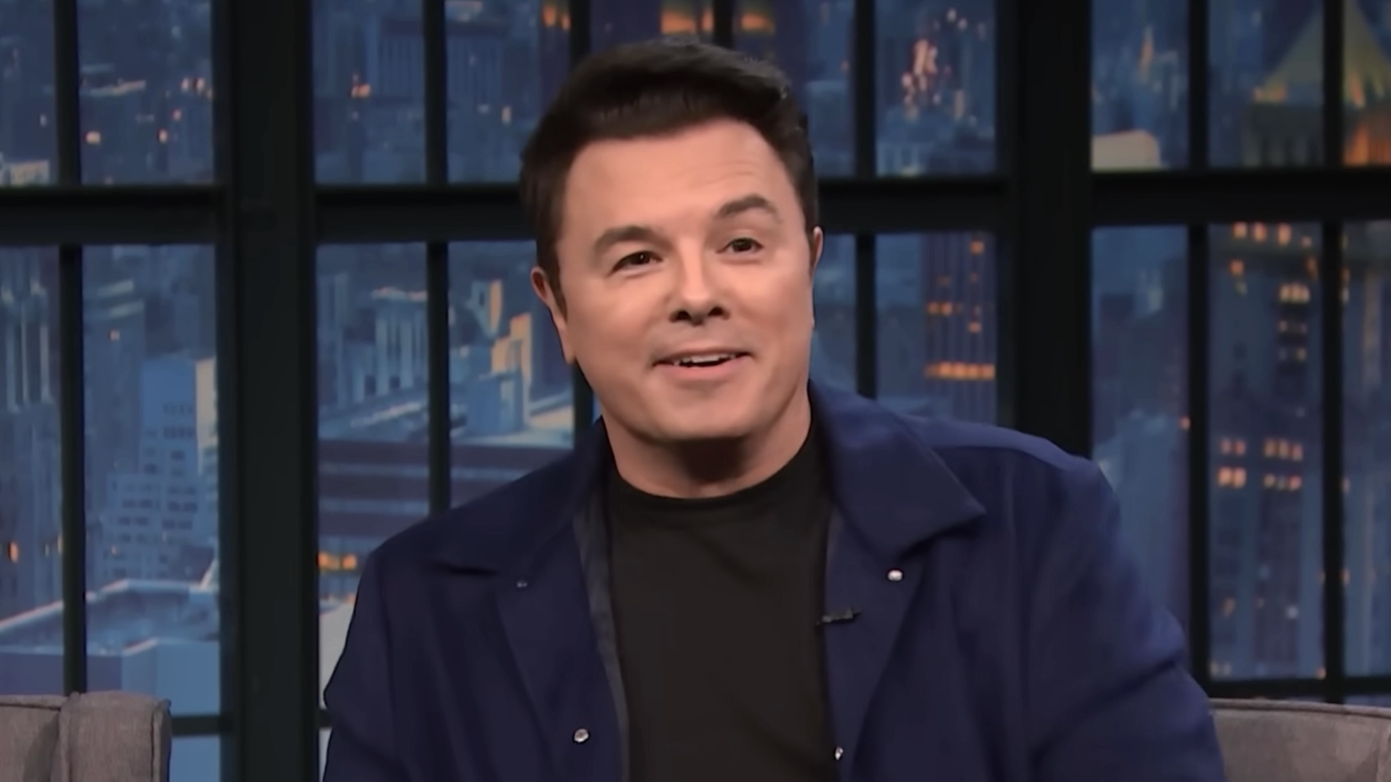 Seth MacFarlane smirking while telling story on Late Night with Seth Meyers
