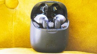 the JBL Tune 225TWS true wireless earbuds in their charging case against a yellow background