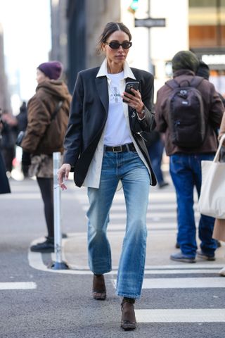 Tylnn wears a blazer, calvin klein t-shirt,, belt, jeans, tights, and open-toe sandals.