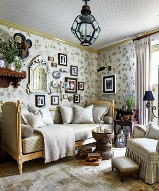 A room with a daybed, light green wallpaper, and many picture frames in a collage.