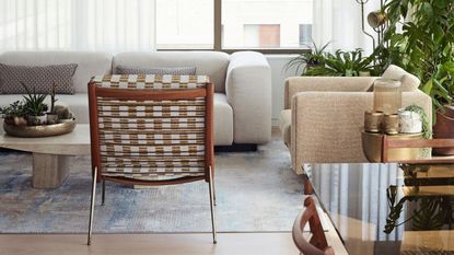 Living room with white boucle armchair, sofa, and large plant