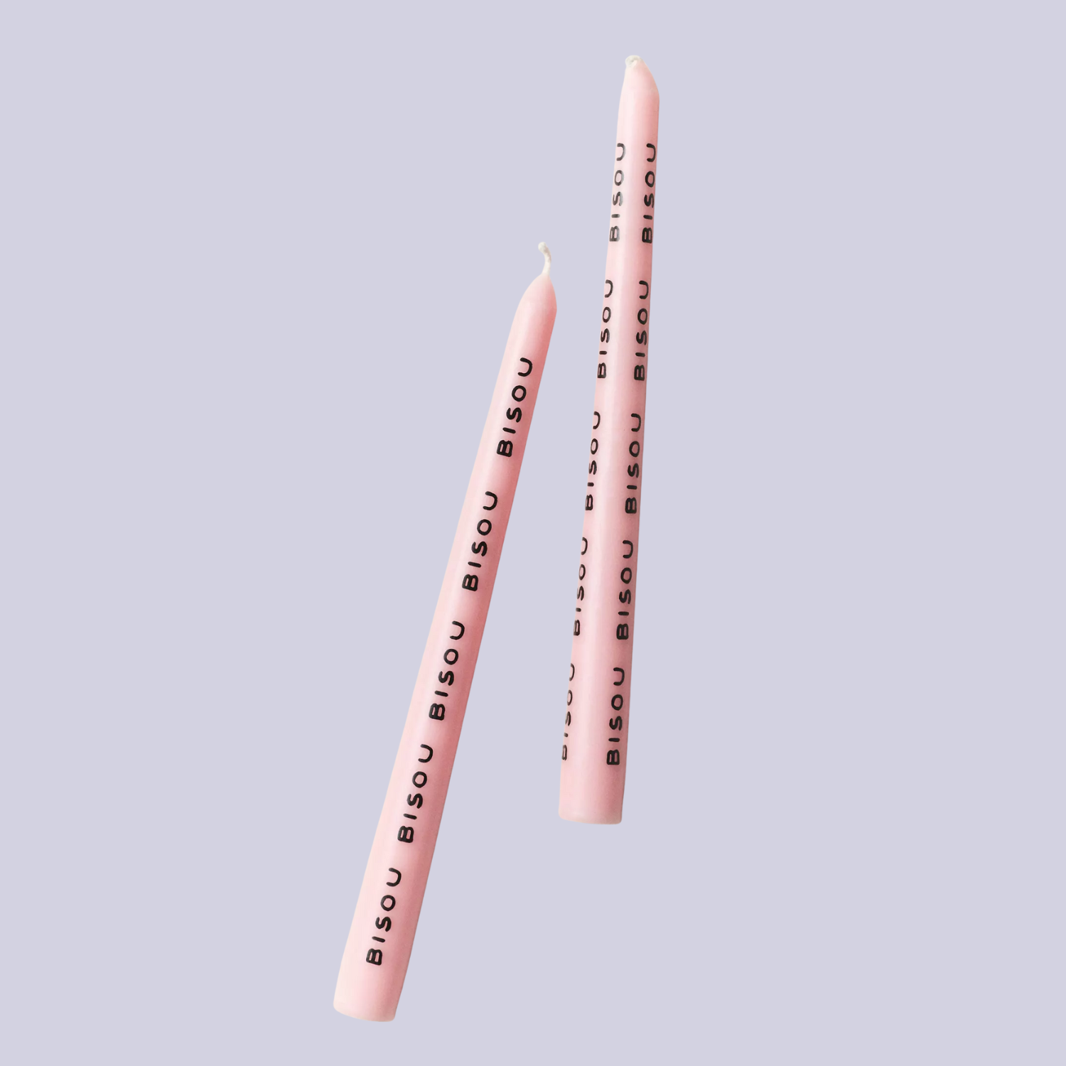 A pair of pink candles with &#039;bisou&#039; writings in black