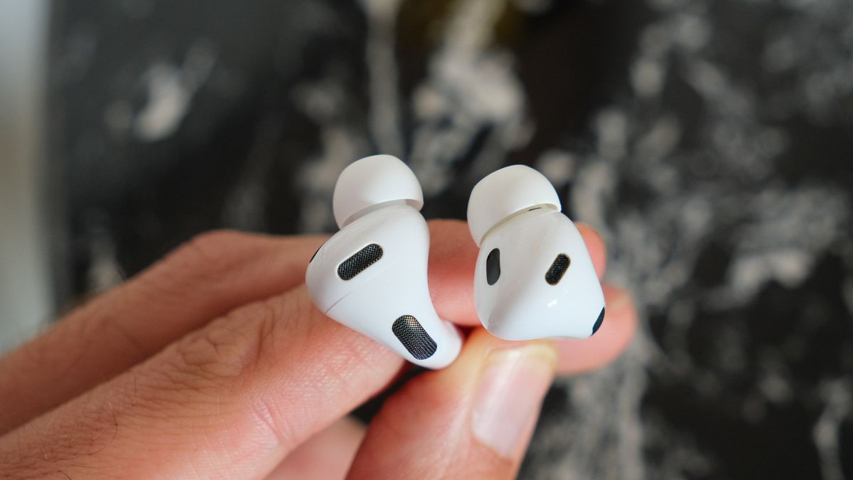 A pair of Apple AirPods Pro 3 ear buds being held between fingers