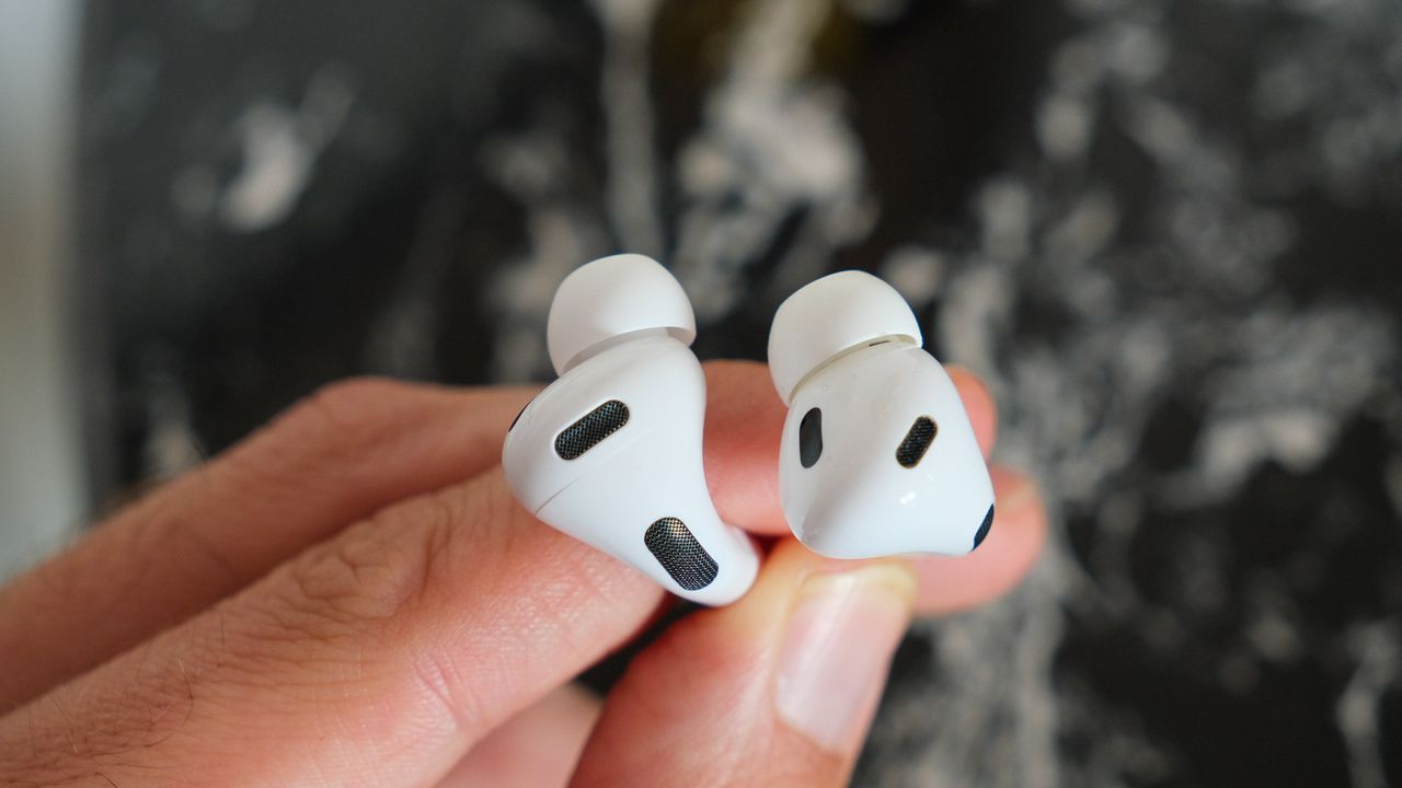 A pair of Apple AirPods Pro 3 ear buds being held between fingers