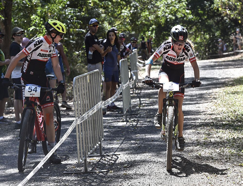 In her final lap, Laura Stigger (Austria) gets cheered on by fellow Austrian waiting to start junior men's race.