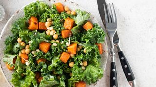 a close up of a kale salad with chick peas and sweet potato on a plate