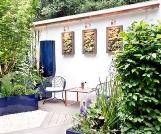 small courtyard garden with simple furniture and garden art on the wall