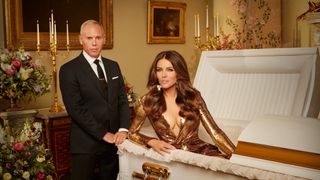 Elizabeth Hurley as The Deceased sitting up in a coffin with her Executor Robert Rinder by her side.