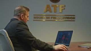 An ATF agent sits at a laptop in a scene from documentary The Takedown: American Aryans