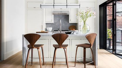 kitchen with island and wooden backed bar stools with white cabinets and steel framed doors