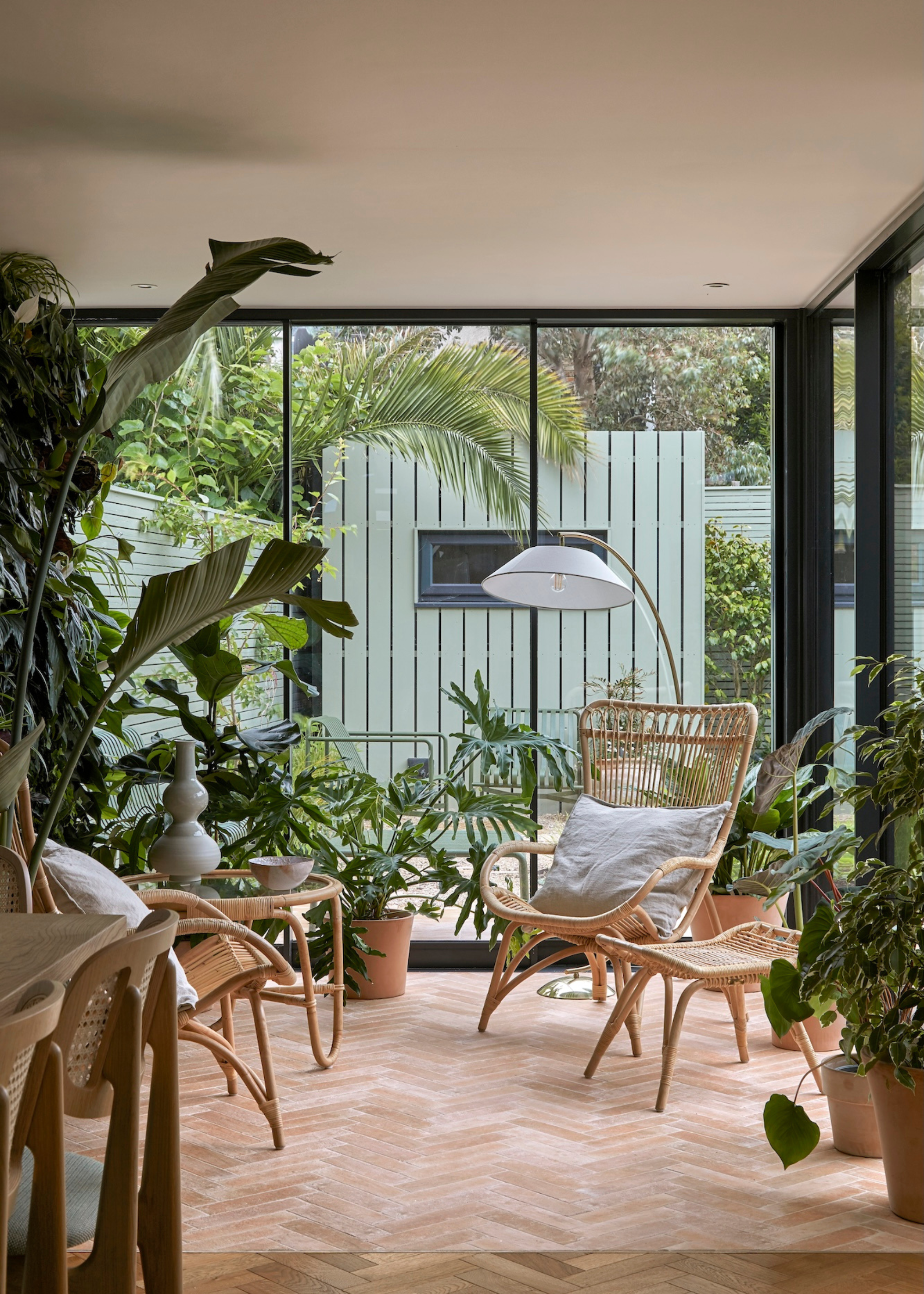 An indoor garden with woven furniture and terracotta potted plants