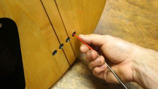 Threading strings through the body of a bass guitar