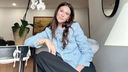 style director sara holzman poses in a blue tweed jacket and black pants