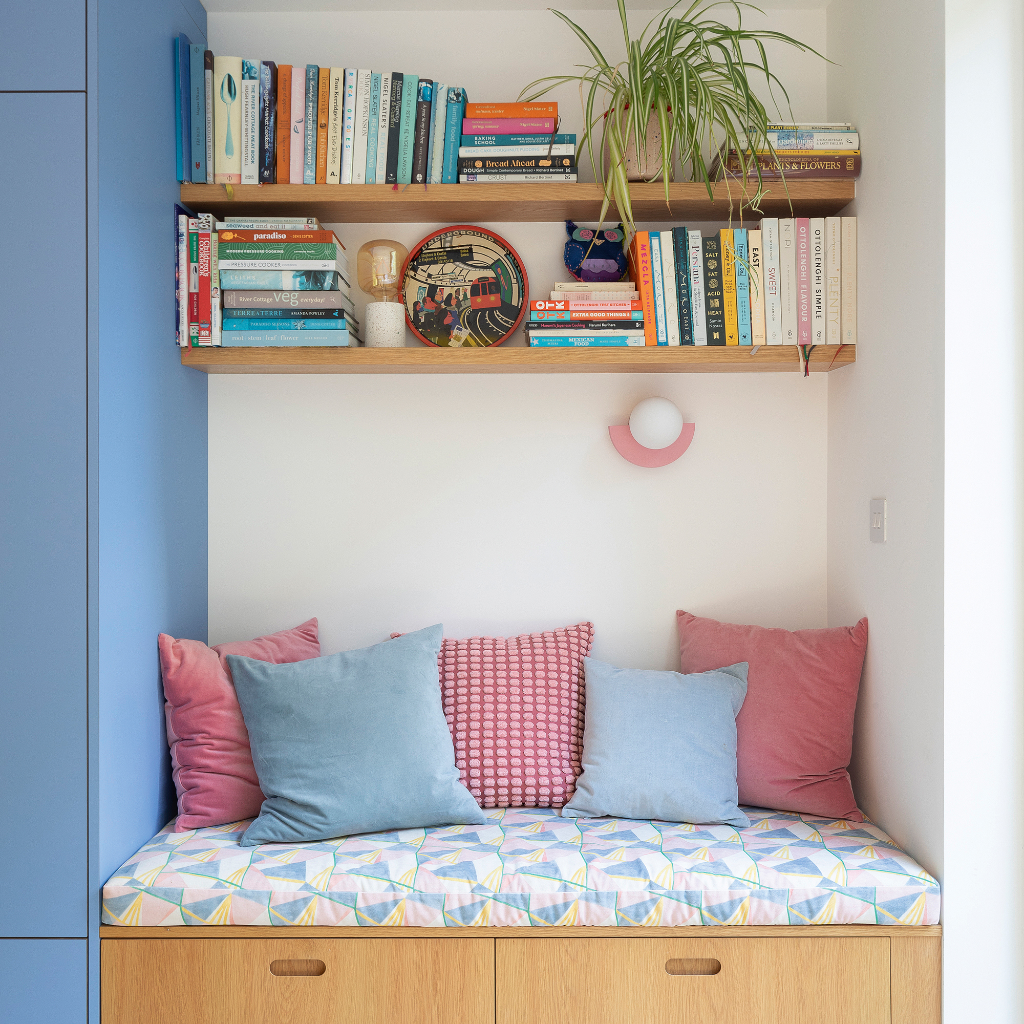 a storage bench with cushions and open shelving with cookbooks