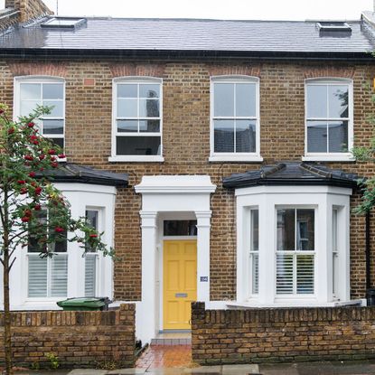 sloping roof house with exposed brick walls and yellow door