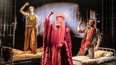 Kiss of the Spider Woman. Three characters dressed elaborately holding their arms aloft