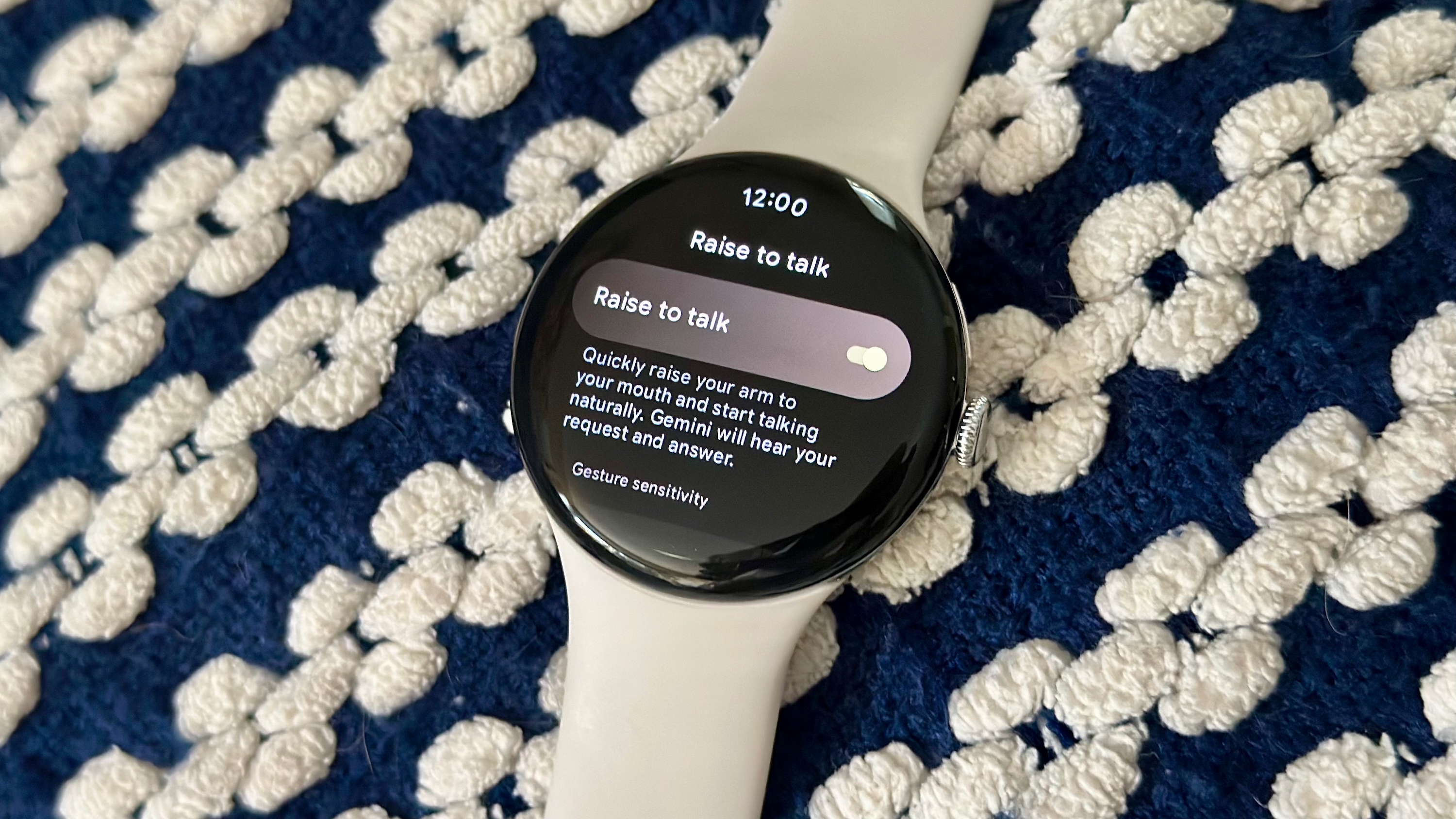 A photo of the Google Pixel Watch 4 on a blanket showing the &quot;Raise to Talk&quot; settings menu, with the feature toggled on.
