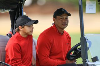 Tiger Woods and Charlie Woods wearing red sat in a golf cart