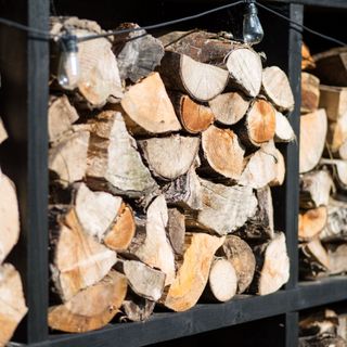 Stacked logs in a dark grey garden wood store