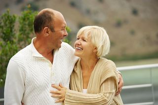 A middle-age couple stands smiling at each other.