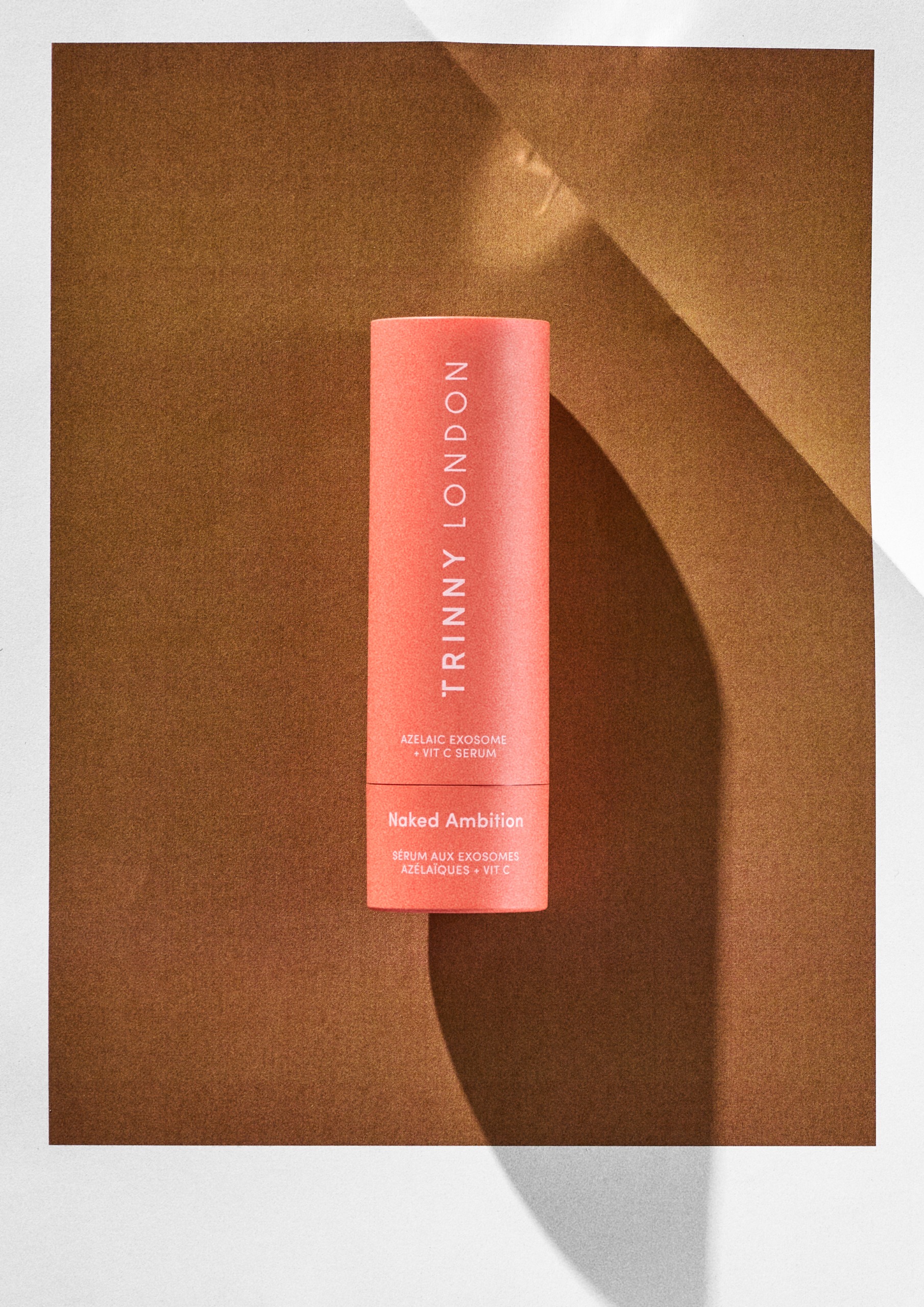 Trinny London Naked Ambition AZELAIC EXOSOME + VITAMIN C SERUM on an orange background