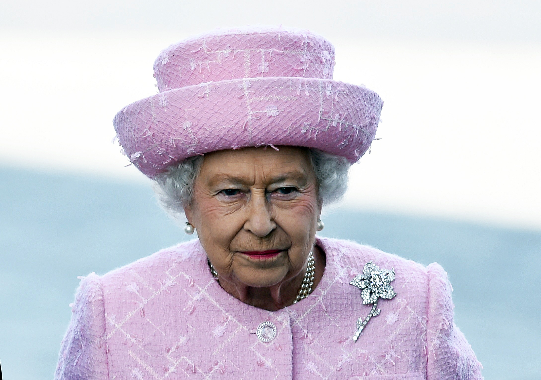 Elizabeth II in a matching pink coat and hat. The Williamson pink diamond is pinned to her lapel