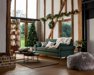 A rustic living room with green upholstered sofa and wooden beams
