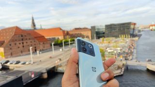 OnePlus 10T hold i hånden med Københavns havn i baggrunden