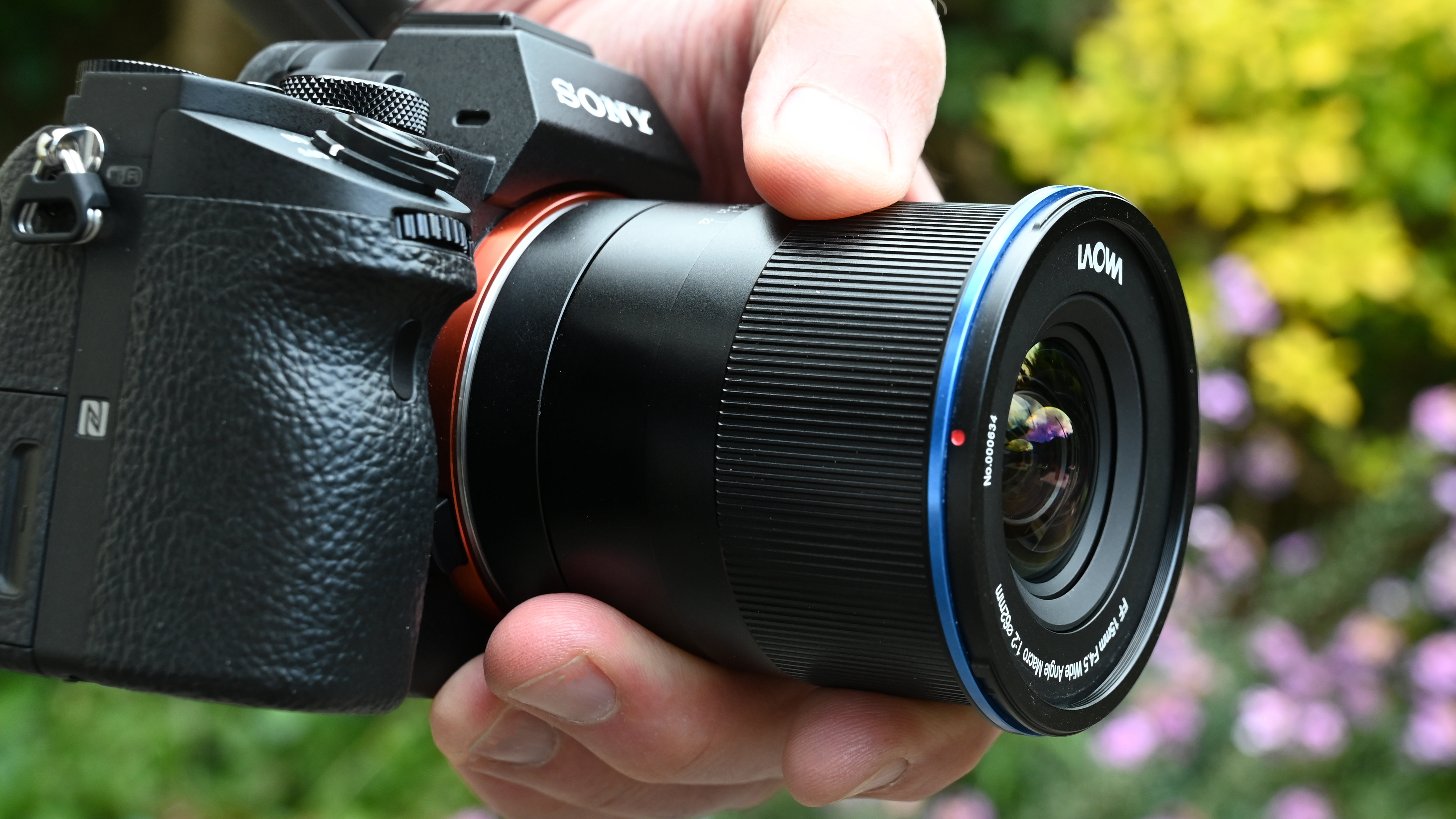 Laowa 15mm f/4.5 0.5x Macro product shot with lens held in hand
