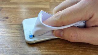 An iPhone SE lens being wiped with a microfiber cloth