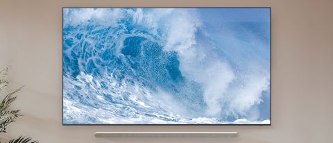 En Samsung QN900B Neo QLED 8K TV hänger på en vägg med härliga blå vågor som bakgrundsbild.