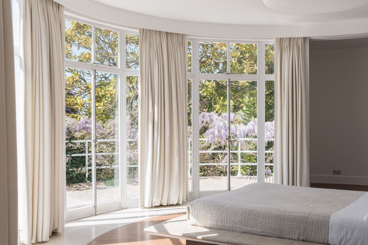 A white bedroom with bifold doors leading onto a balcony
