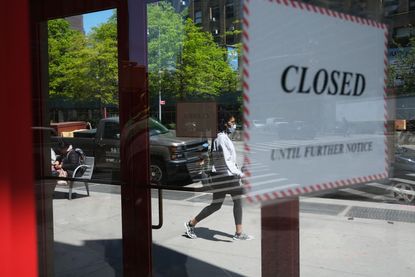 People walk through a shuttered business district in Brooklyn on May 12, 2020 in New York City