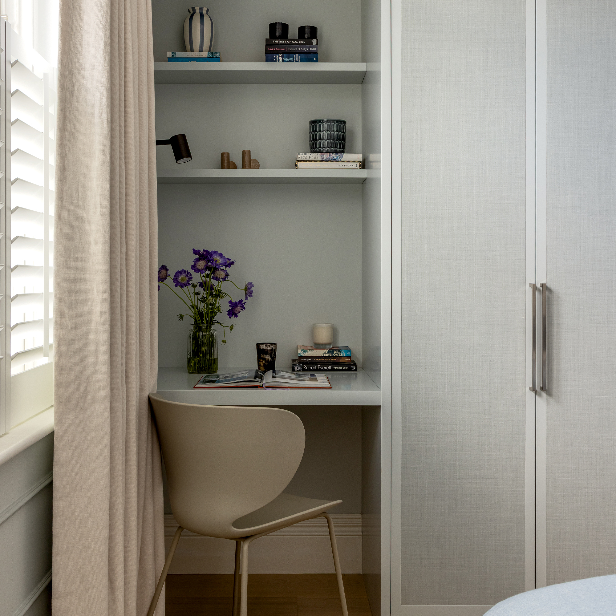 A desk fitted into the alcove shelving beside a wardrobe in the bedroom
