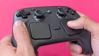 Valve Steam Controller (2026) held in two hands against a magenta card background