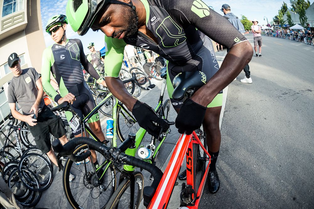 Justin Williams adjusts teammate Joelle Numainville's bike before he uses it in the Canadian race