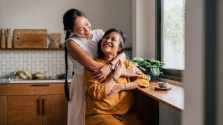 Woman hugging mother in kitchen