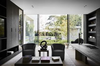Black wooden living space with two black arm chairs and a table with books on